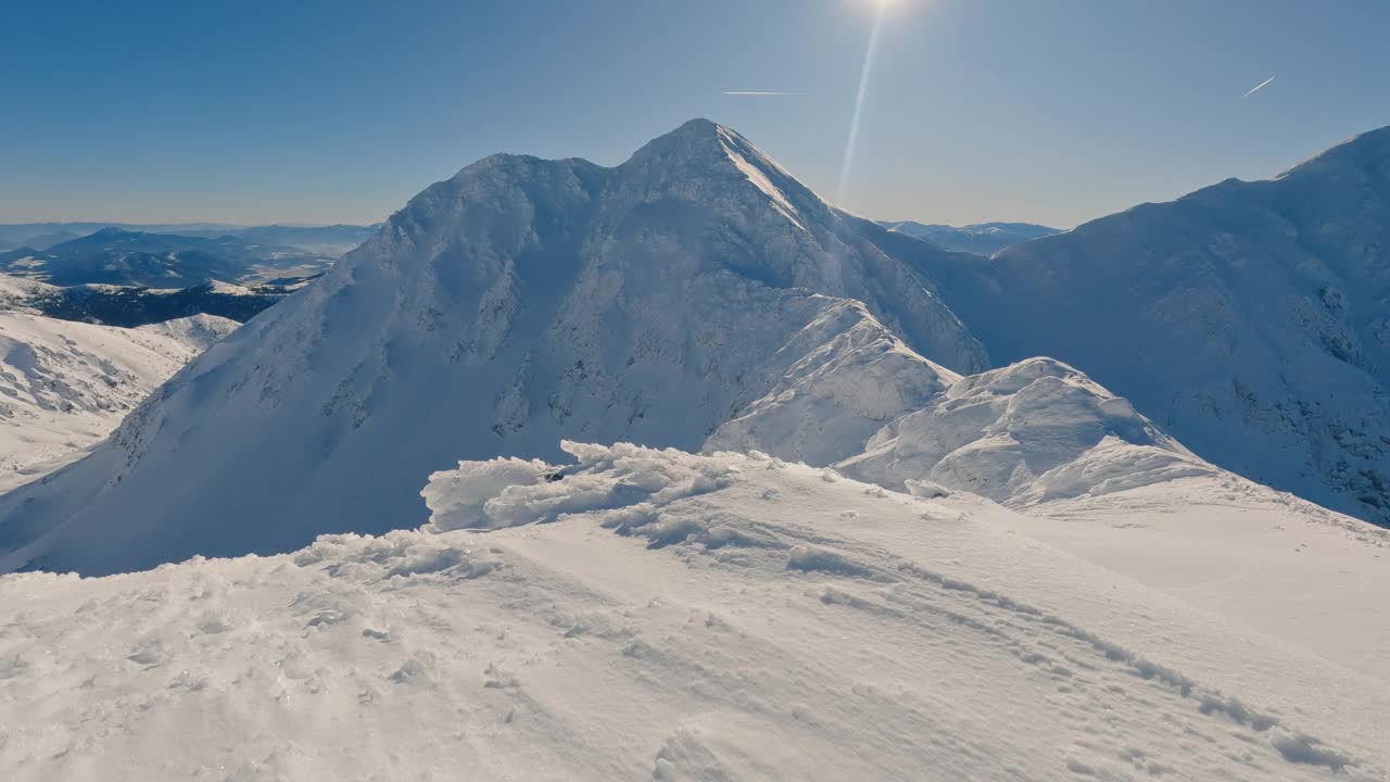 冰封的冬季阿尔卑斯雪山在阳光明媚的日子里有着蔚蓝的天空，倾斜起来露出镜头，冒险登山视频下载