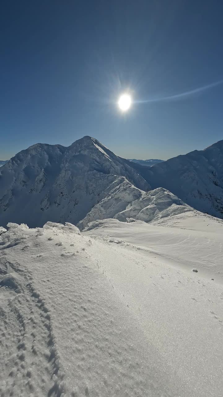 垂直视频冻结冬季阿尔卑斯山雪山在晴朗的日子与蓝天，冒险登山的背景视频下载