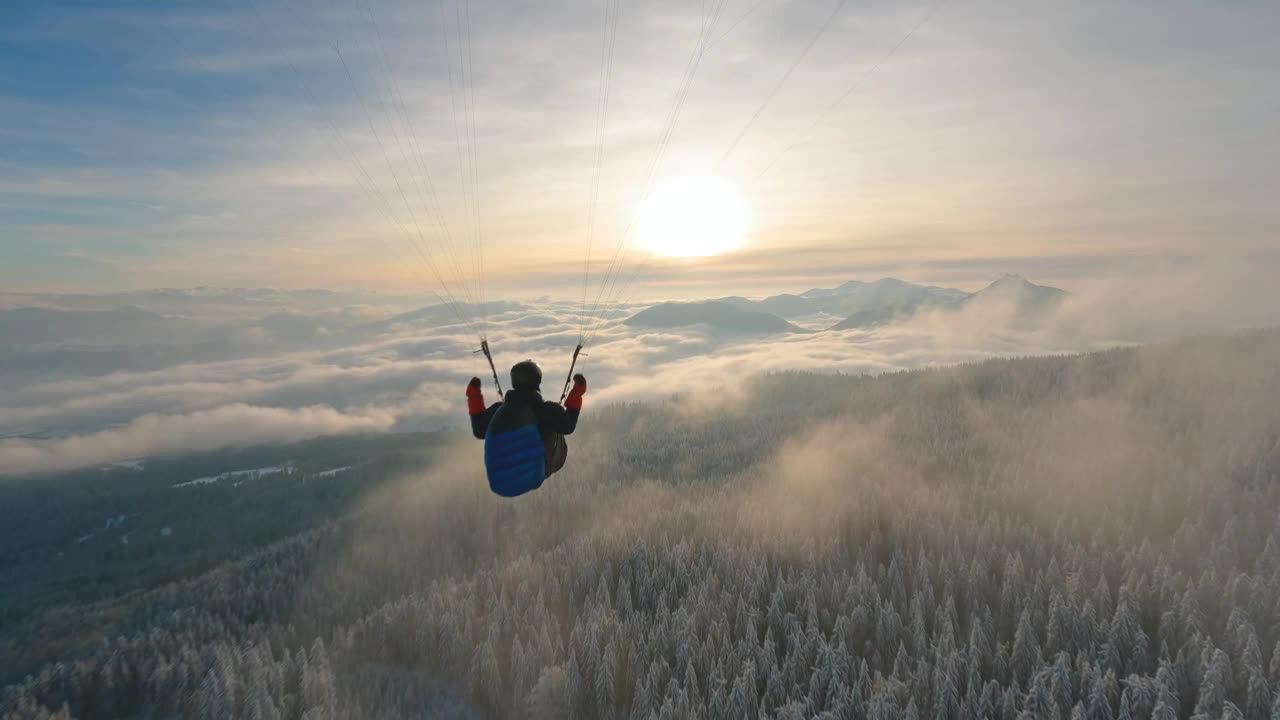 滑翔伞飞行梦想自由在雾蒙蒙的冬季森林山脉在日落视频下载
