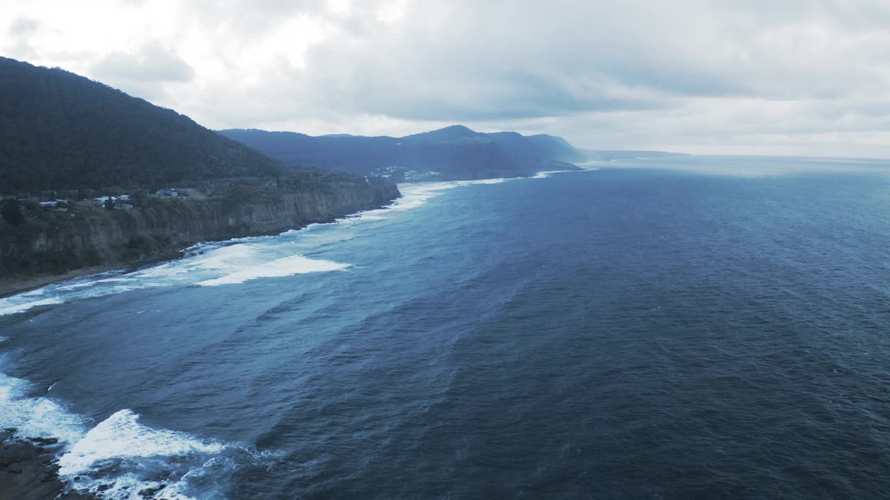 空中俯瞰多云天空下波涛汹涌的海面下宁静的岩层——澳大利亚卧龙岗视频素材