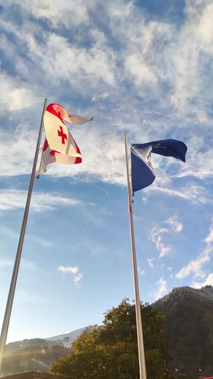 在阳光明媚的日子里，格鲁吉亚和欧盟的国旗迎风飘扬视频下载