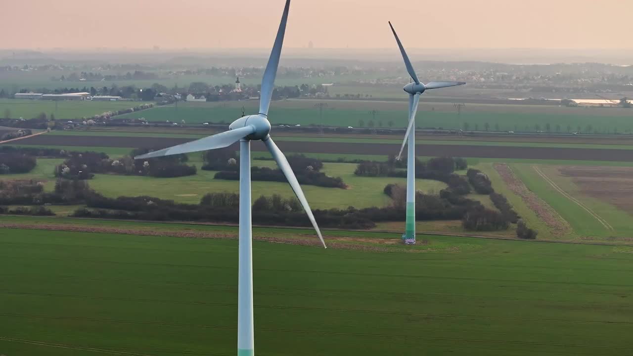 日出时的风力涡轮机。高速公路前的风力涡轮机的长焦镜头。绿色的田野和橙色的天空。视频素材