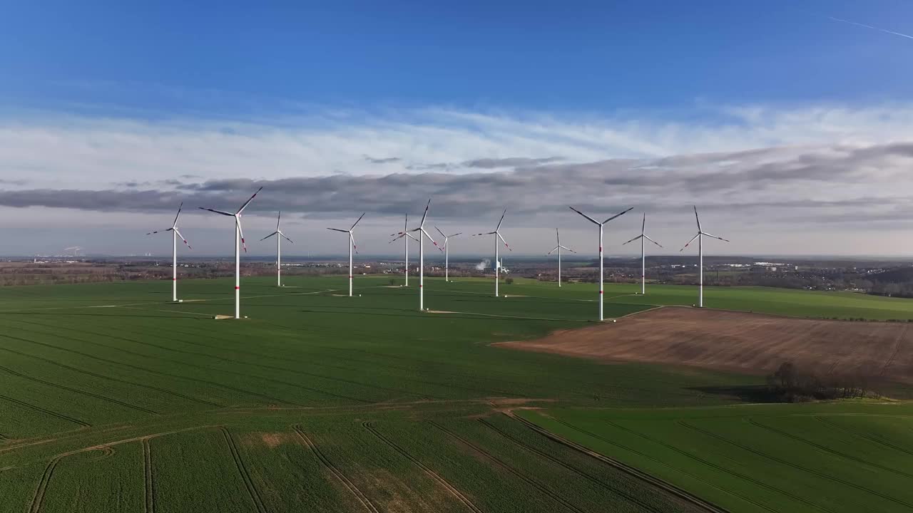 向风力发电场缓慢飞行。蓝天白云。春天田野上的风力涡轮机。视频下载
