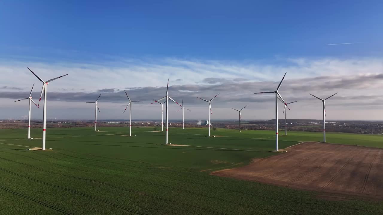 早上沿着风电场飞行。田地里的风力涡轮机。耕地蓝天白云。视频下载