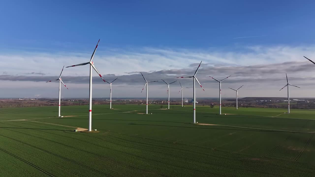 风力发电场的远摄照片。向风力涡轮机飞去。晴朗的春日，很少有云。耕地上的风力涡轮机。视频素材