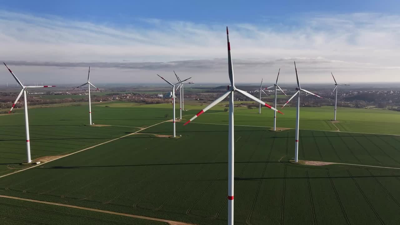 一个大型风力发电场的远摄照片。向风力涡轮机飞去。有几个风力涡轮机的耕地。视频下载