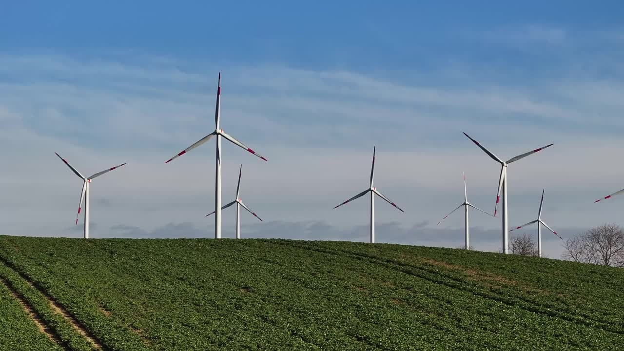 山丘上风力涡轮机的远摄照片。缓慢上升。更多的风力涡轮机即将问世。田野里的风电场。视频素材