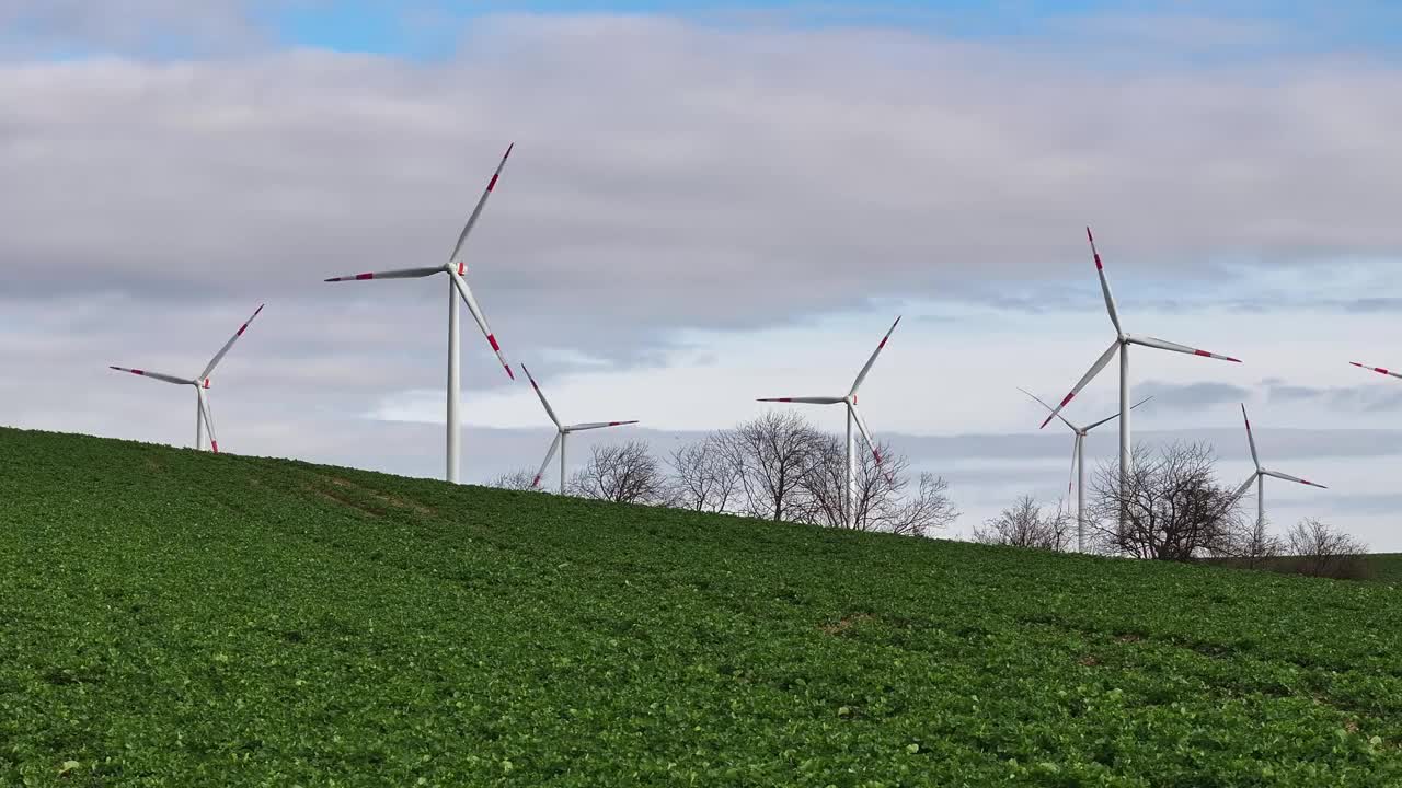 低空飞越田野。背景是风力涡轮机。前景从右向左移动。山上的风力发电场。视频下载