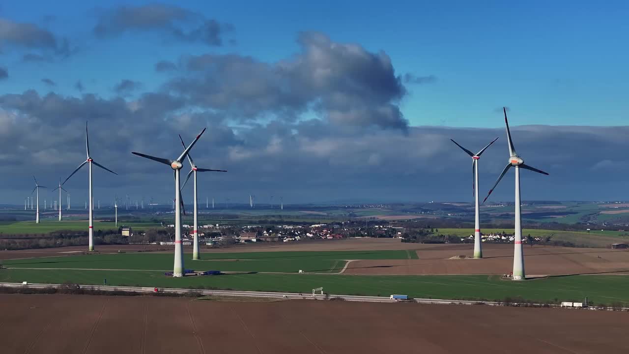 风力发电场的远摄照片。沿着高速公路飞行。风力涡轮机在前景和地平线上。交通繁忙的高速公路。视频下载