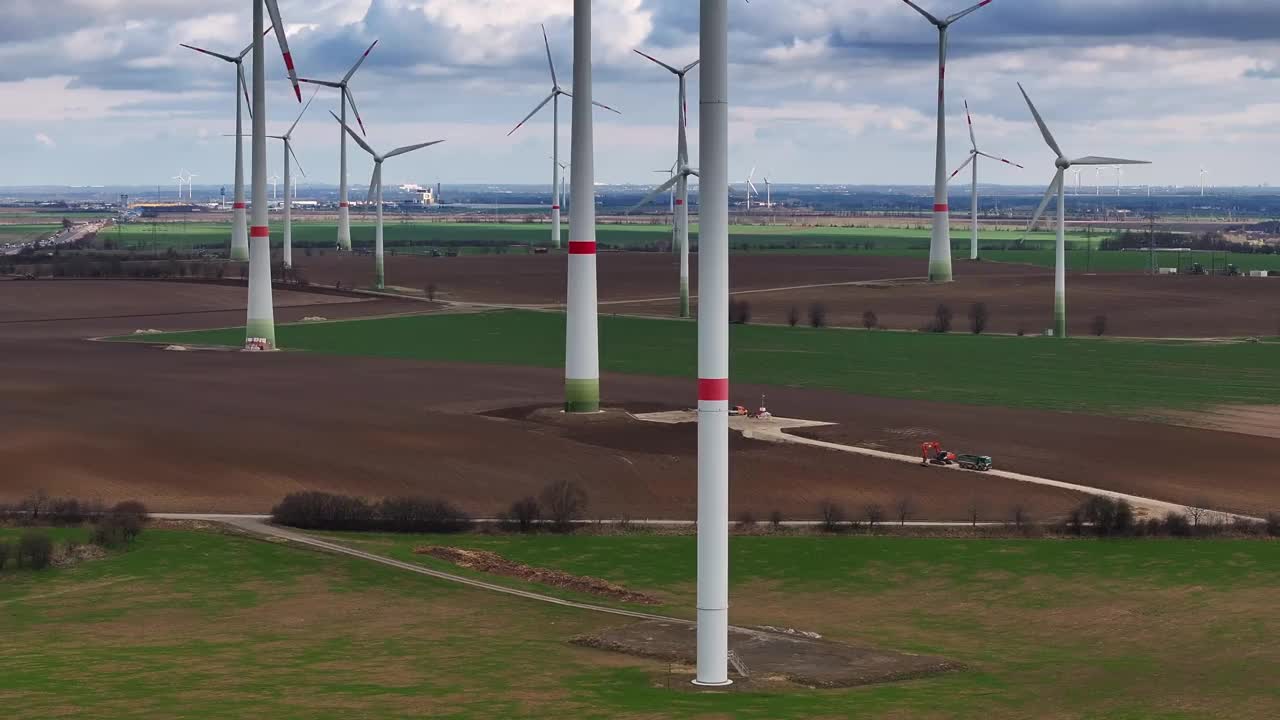 飞上高塔到贡多拉。一个大型风电场的风力涡轮机的远摄照片。平坦的土地上有风力涡轮机。远处有一条高速公路。视频下载