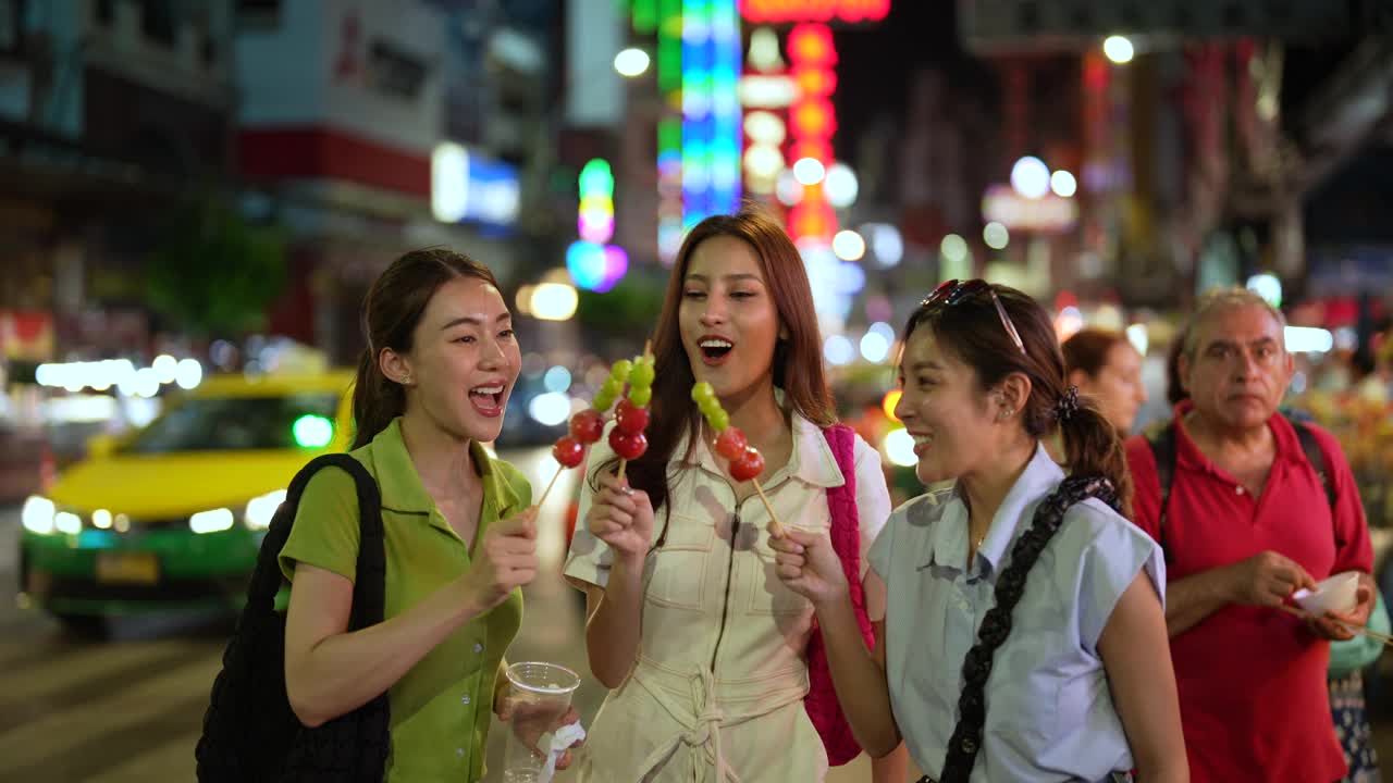 亚洲游客晚上在城市里散步。享受夜市的街头小吃。视频素材