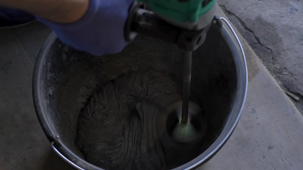在黑桶中混合石膏胶粘剂，用于贴墙视频下载