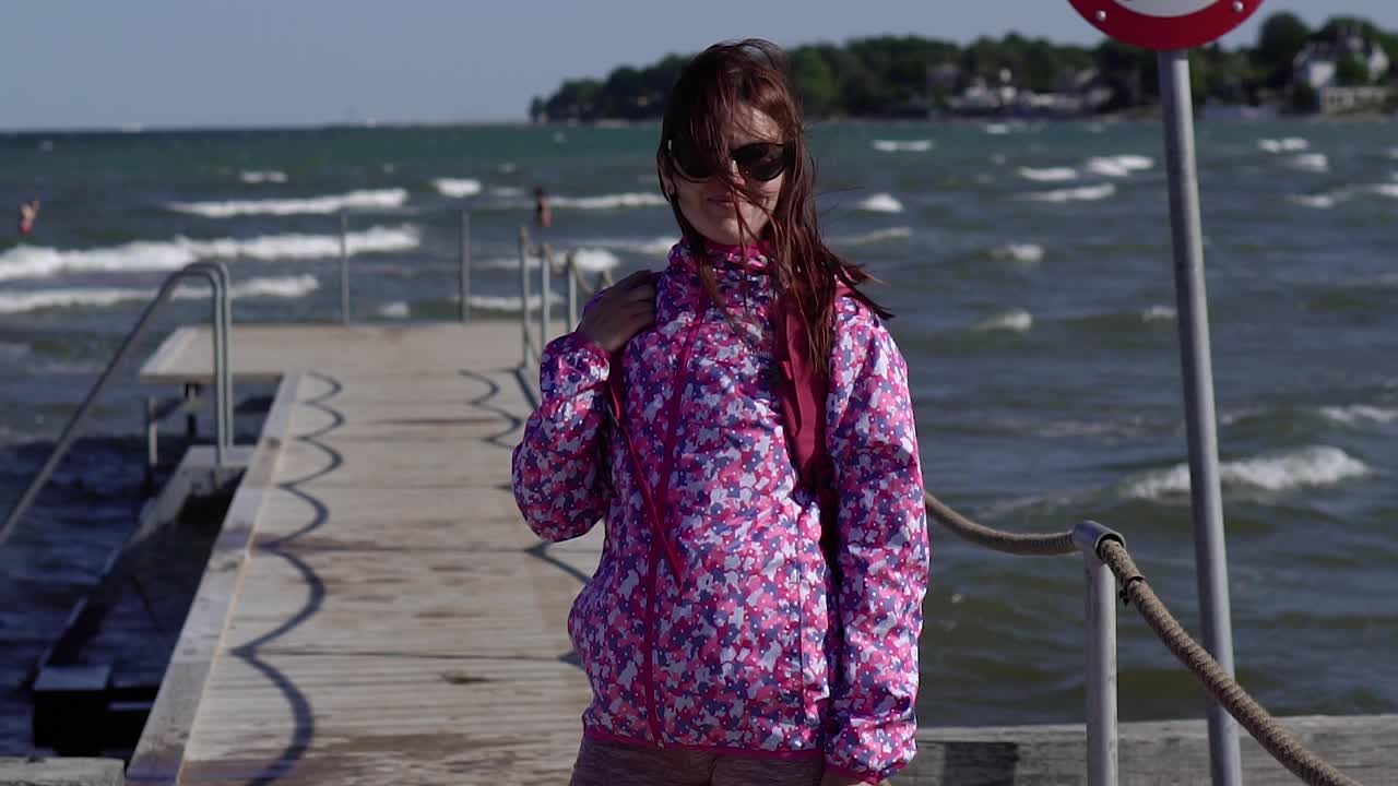 海中。一个女人站在码头上，以大海为背景。视频下载