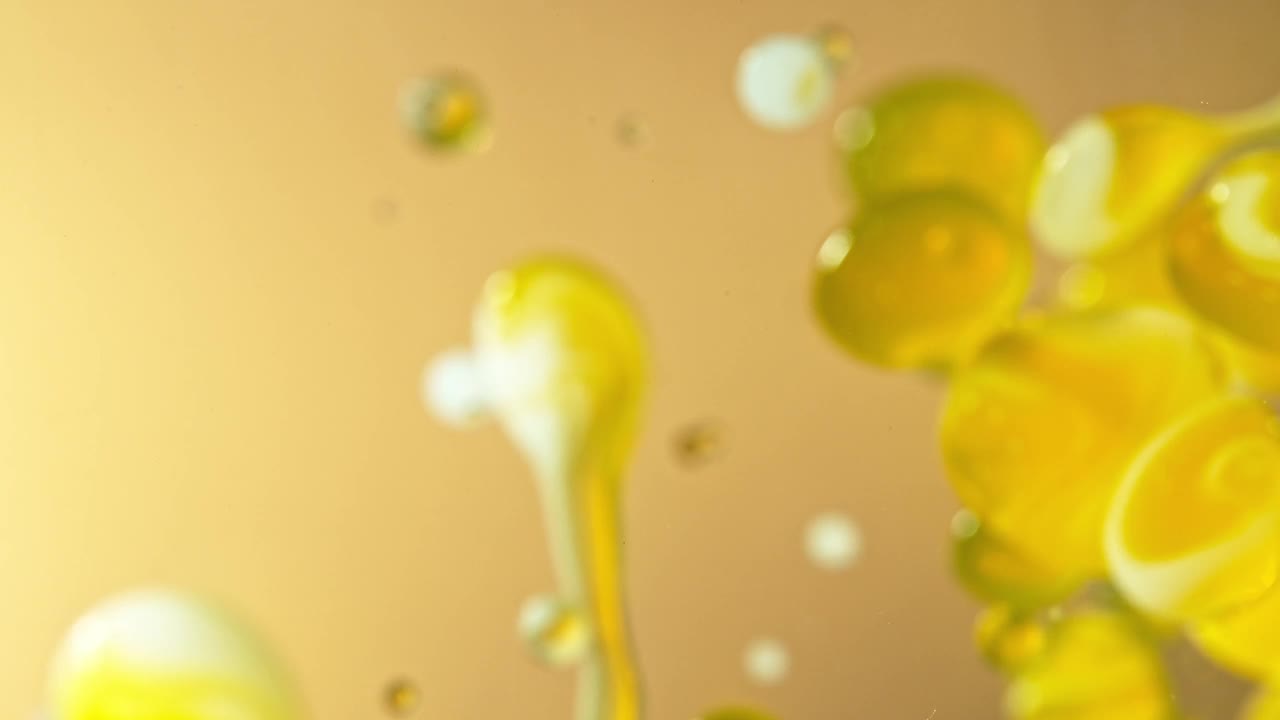超级慢动作拍摄移动油和牛奶泡沫在金色背景，化妆品概念视频下载