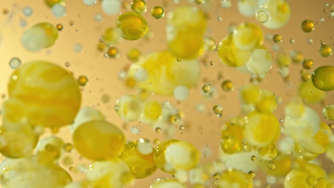 超级慢动作拍摄移动油和牛奶泡沫在金色背景，化妆品概念视频下载