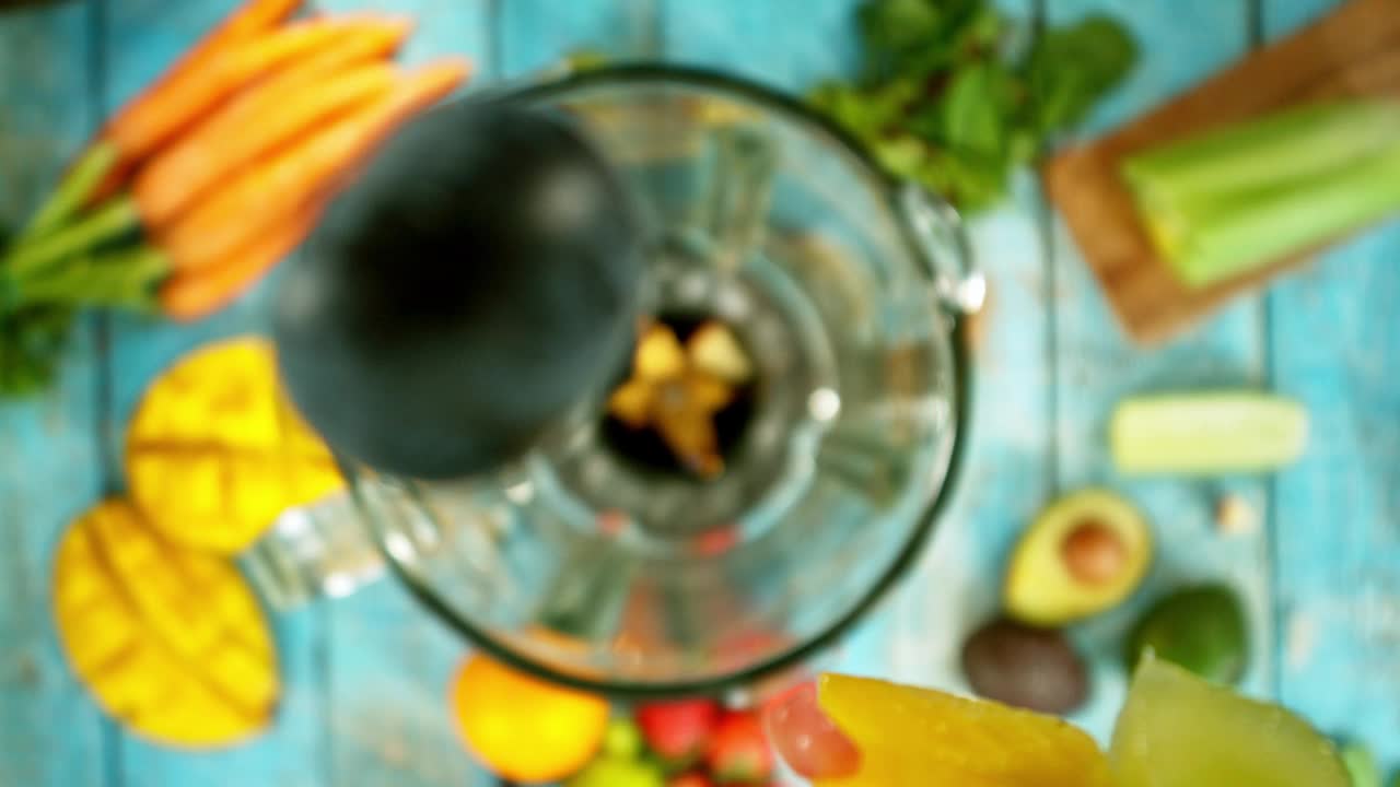在搅拌器中混合水果和蔬菜的超级慢动作，相机运动，顶部镜头视频下载