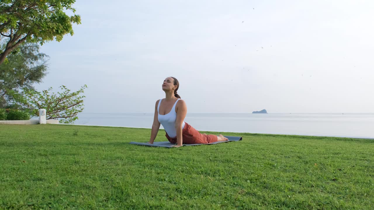 海边年轻女子的晨间瑜伽体式视频下载