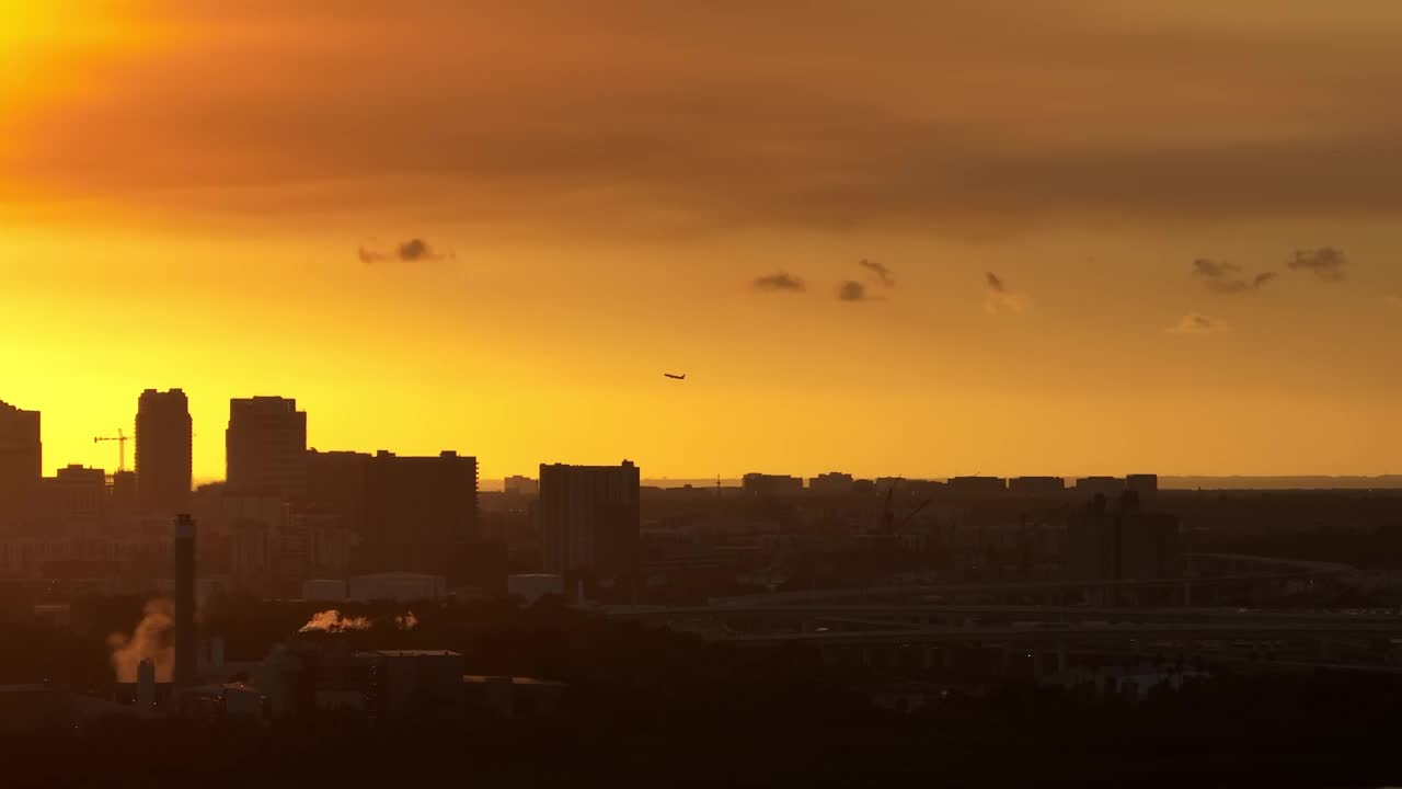在日落时分，美国佛罗里达州坦帕市市中心上空起飞的喷气式客机鸟瞰图。现代美国市中心高耸的摩天大楼的黑色剪影视频下载
