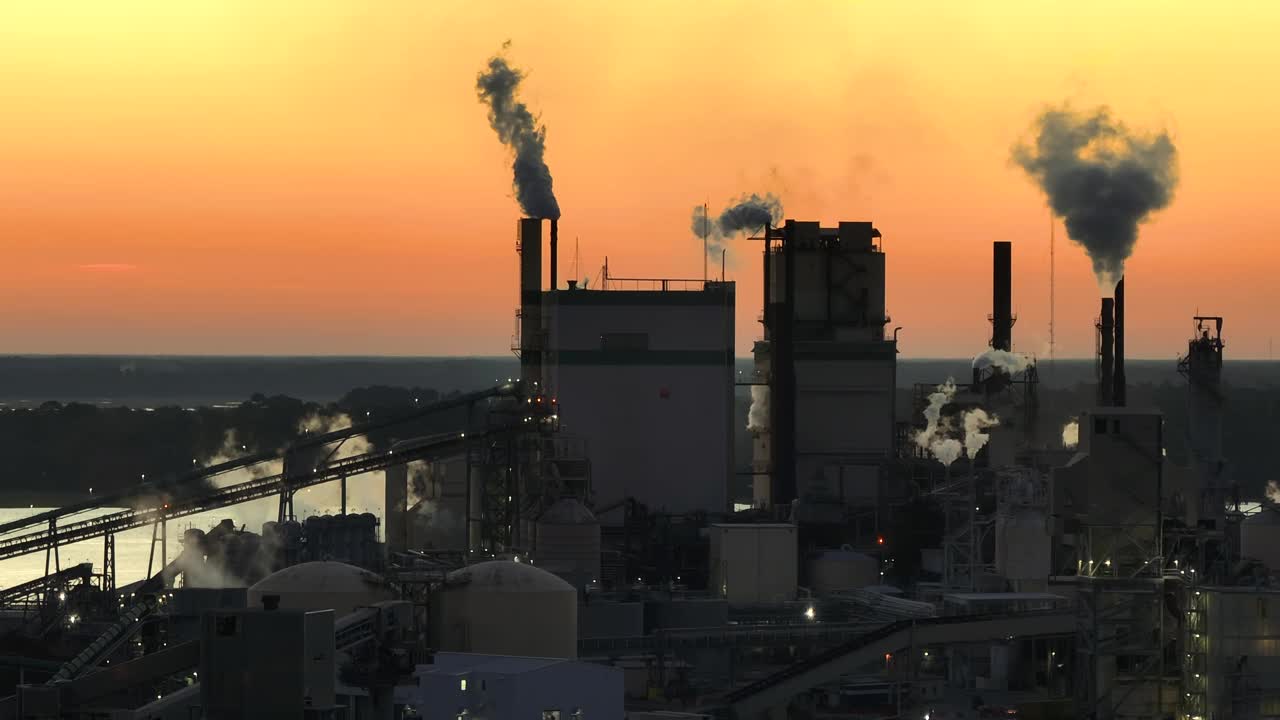 大型厂房，生产过程中产生的烟雾上升，污染了制造场地的大气。夕阳下的工业用地视频下载