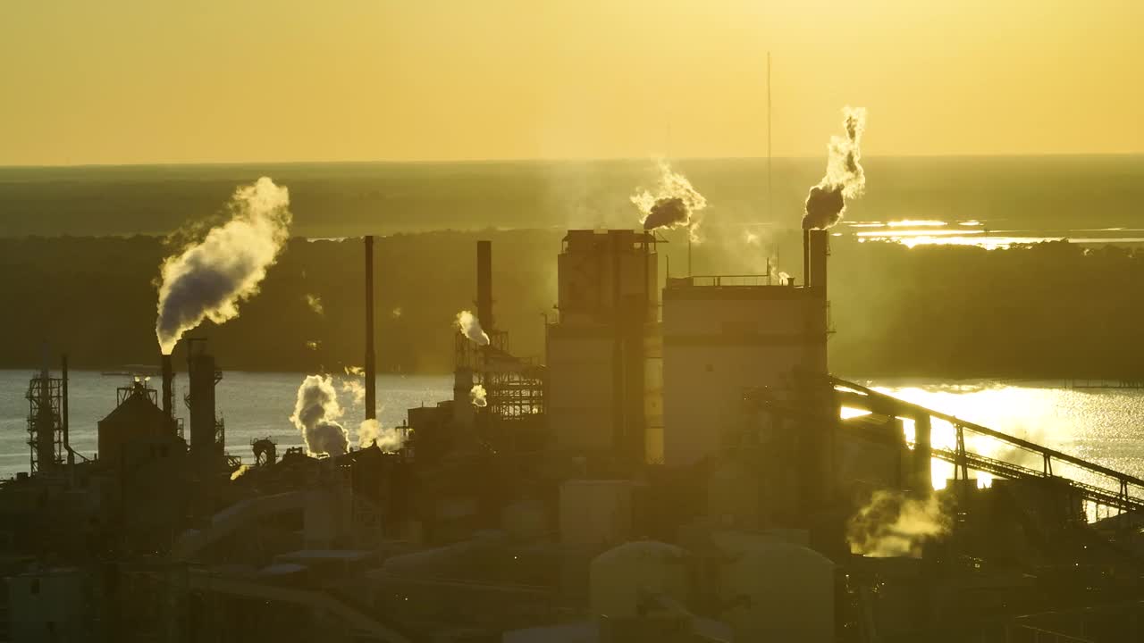 木材加工厂鸟瞰图，生产过程中产生的烟雾污染了工厂制造场的大气。夕阳下的工业用地视频下载