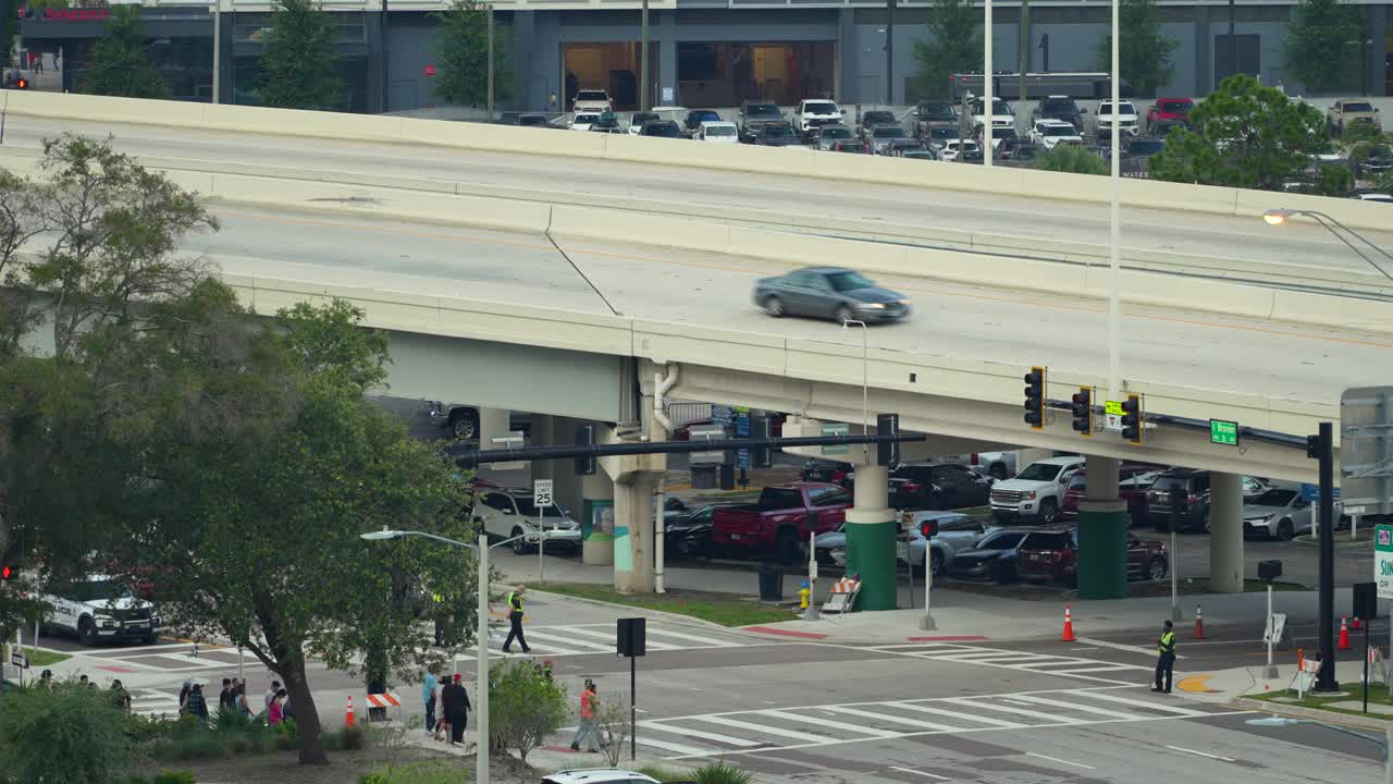 在高峰时段，在人行横道上行走的行人和在佛罗里达城市街道上缓慢行驶的汽车造成的交通堵塞视频下载