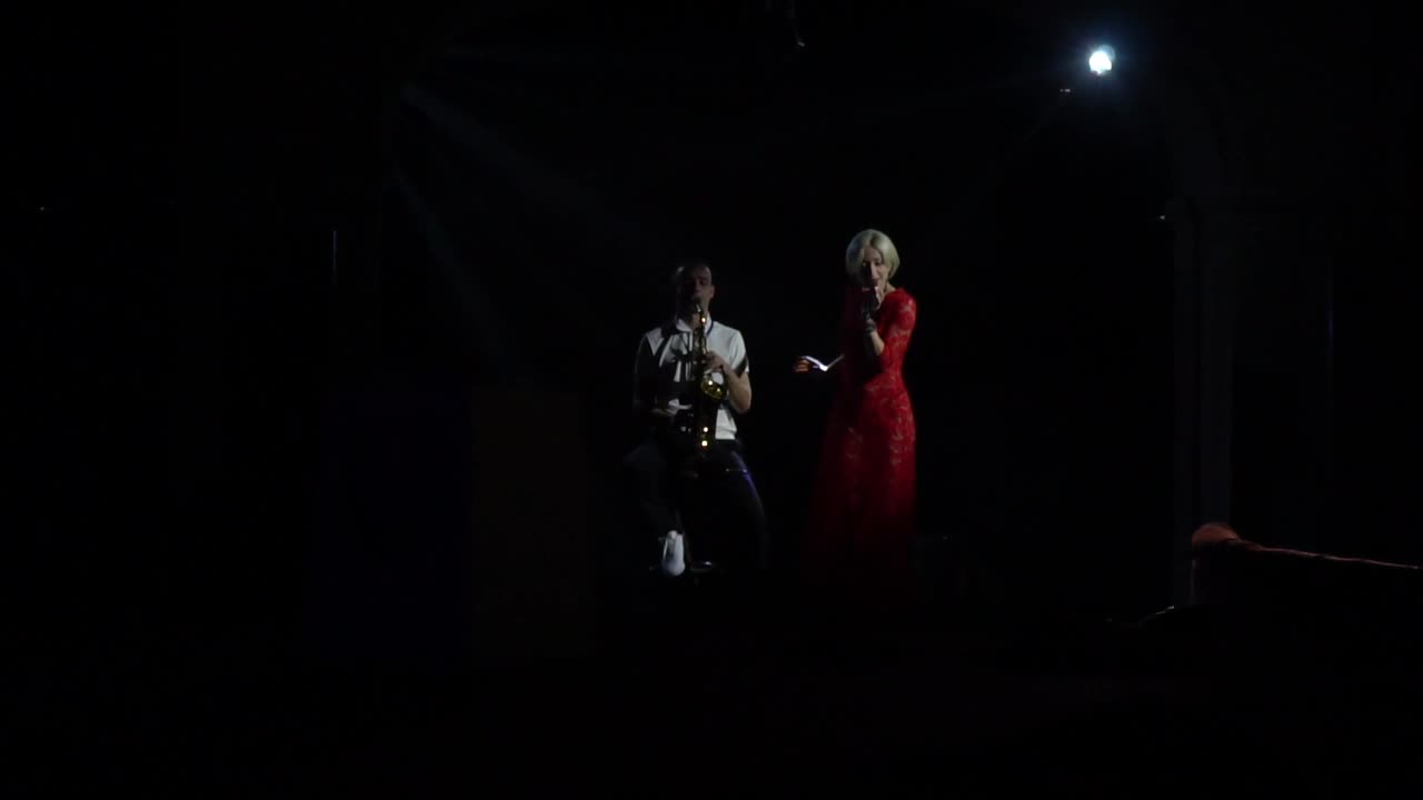 二重唱是在舞台上表演在戏剧性的灯光，歌手和萨克斯管演奏家视频下载