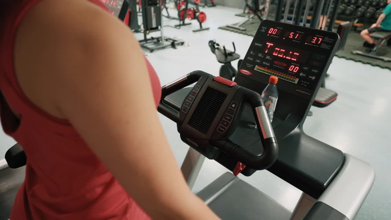 手持拍摄的运动年轻女子穿着运动服检查智能手表和跑步机在现代健身房视频下载