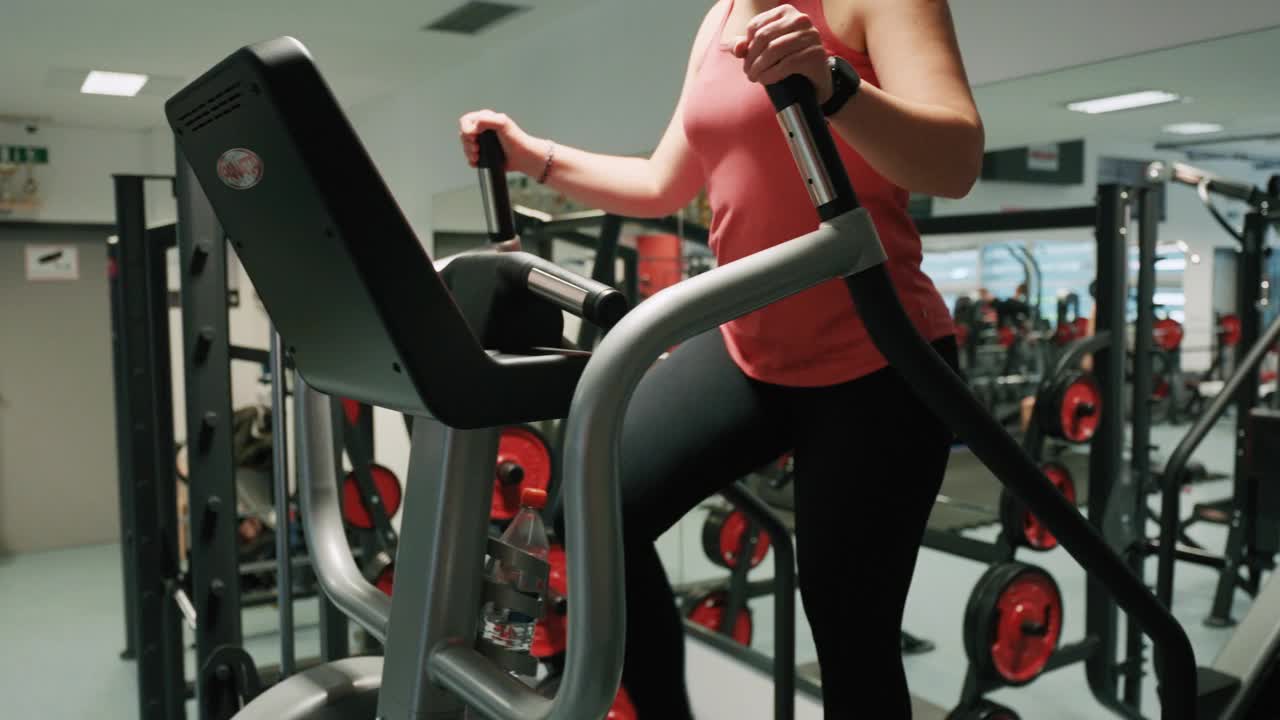 女子在现代健身房步进模拟器上进行有氧训练的手持镜头视频下载