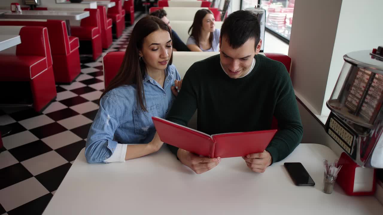 一对年轻夫妇，在一家复古快餐店看菜单视频下载