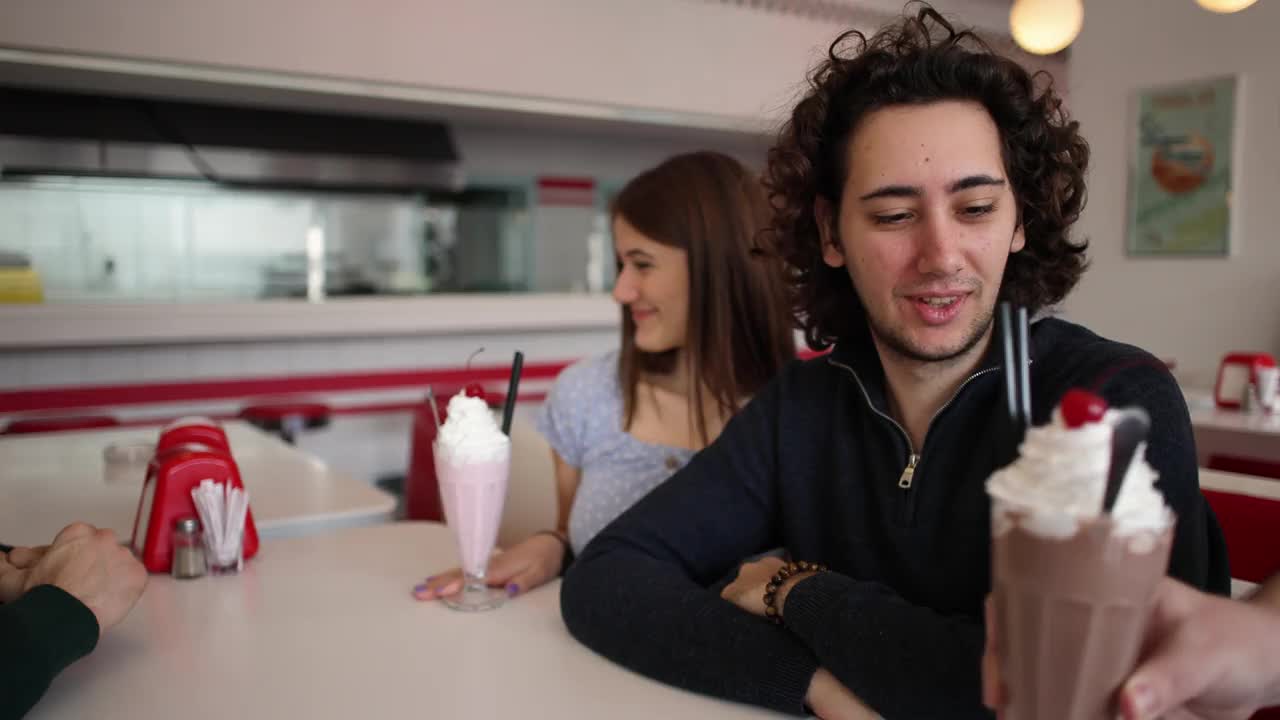年轻的白种人喝着奶昔，在一家复古的快餐店进行四人约会视频下载