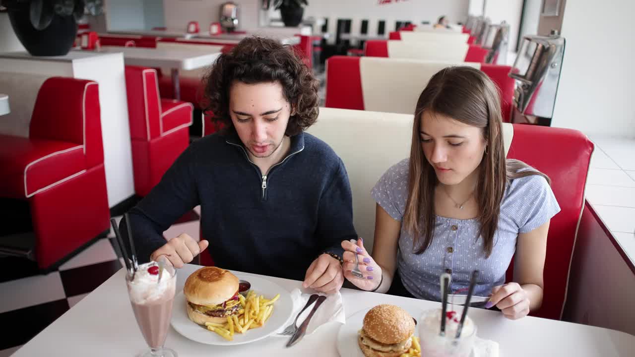 白人男女在复古快餐店吃汉堡和奶昔视频下载
