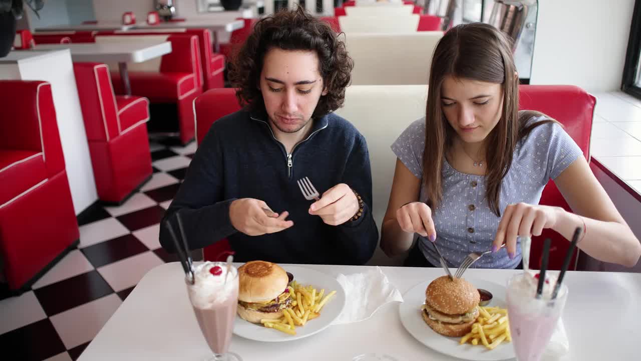 白人男女在复古快餐店吃汉堡和奶昔视频下载