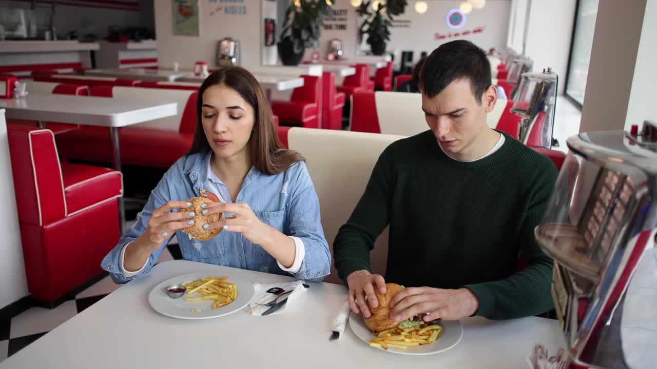 男女朋友在复古餐厅吃汉堡和薯条视频下载