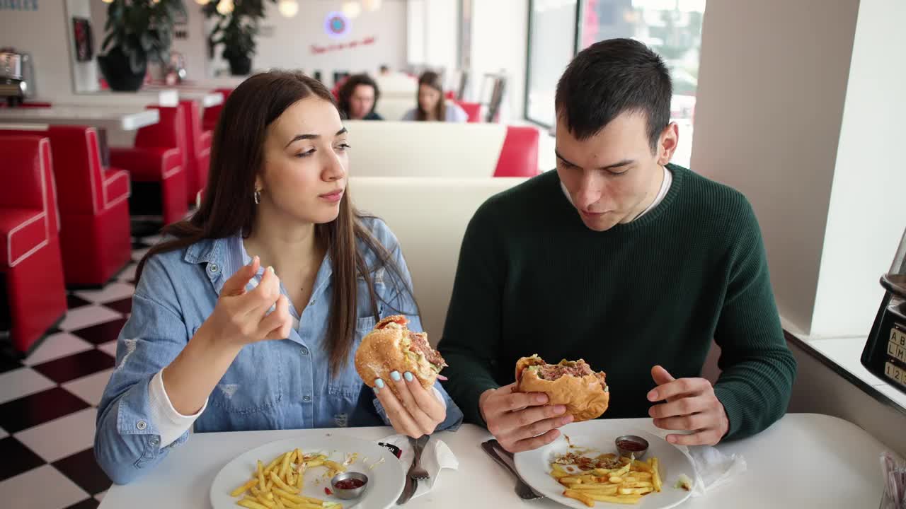 一对年轻夫妇在一家复古的快餐店里分享一个汉堡视频下载