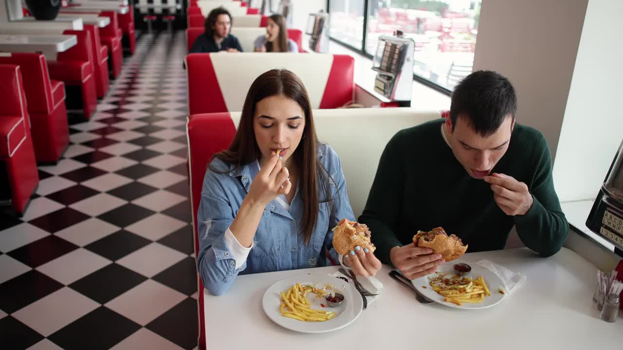年轻夫妇在复古餐厅吃汉堡视频下载
