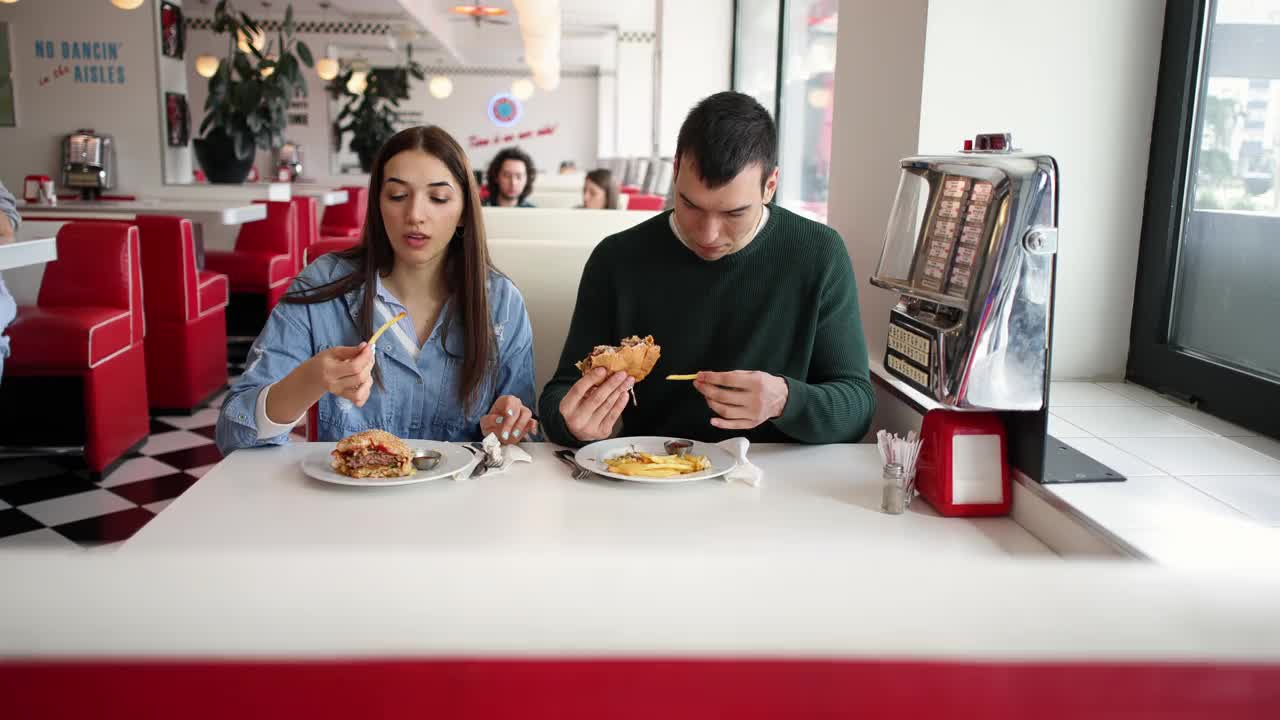一对白人夫妇在一家复古快餐店里吃薯条和汉堡视频下载