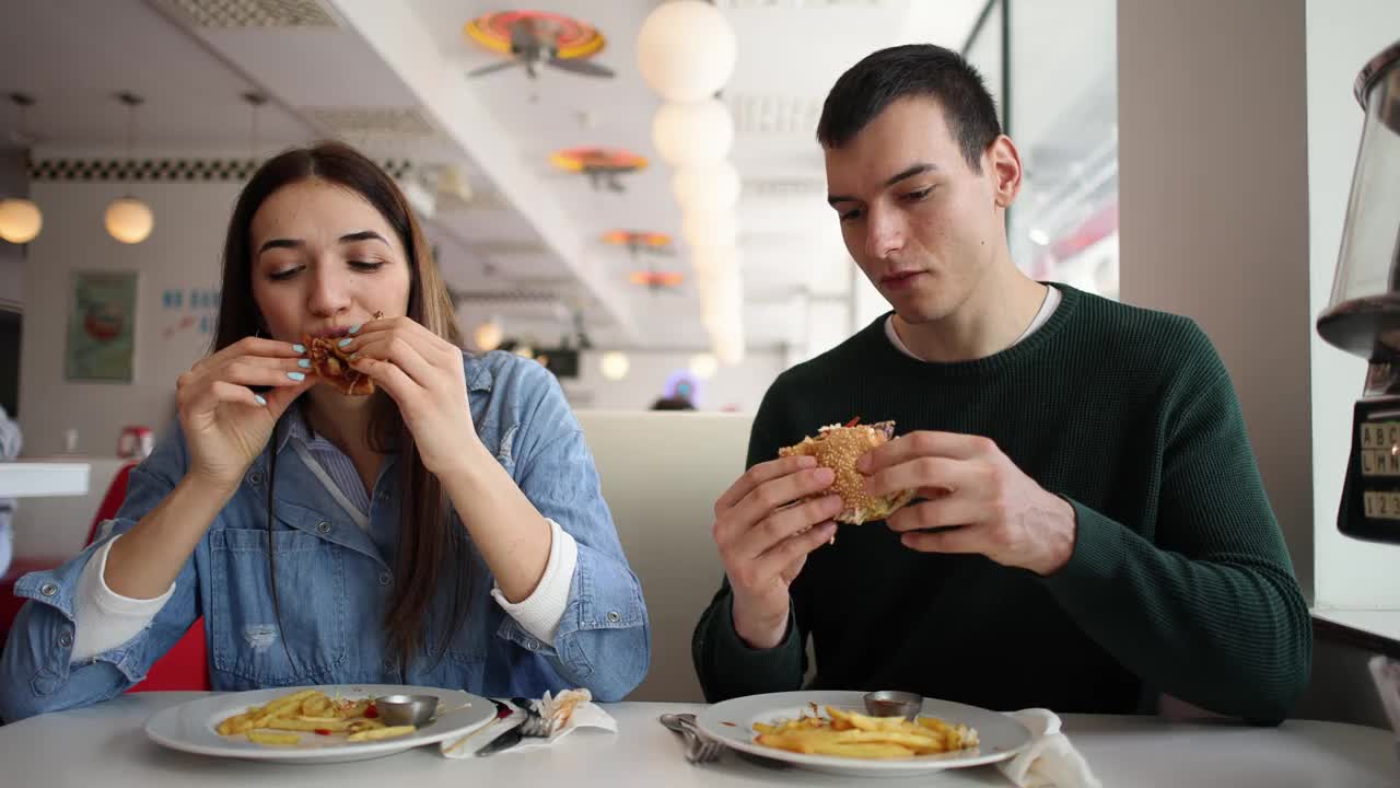 年轻夫妇在复古快餐店吃薯条和汉堡视频下载
