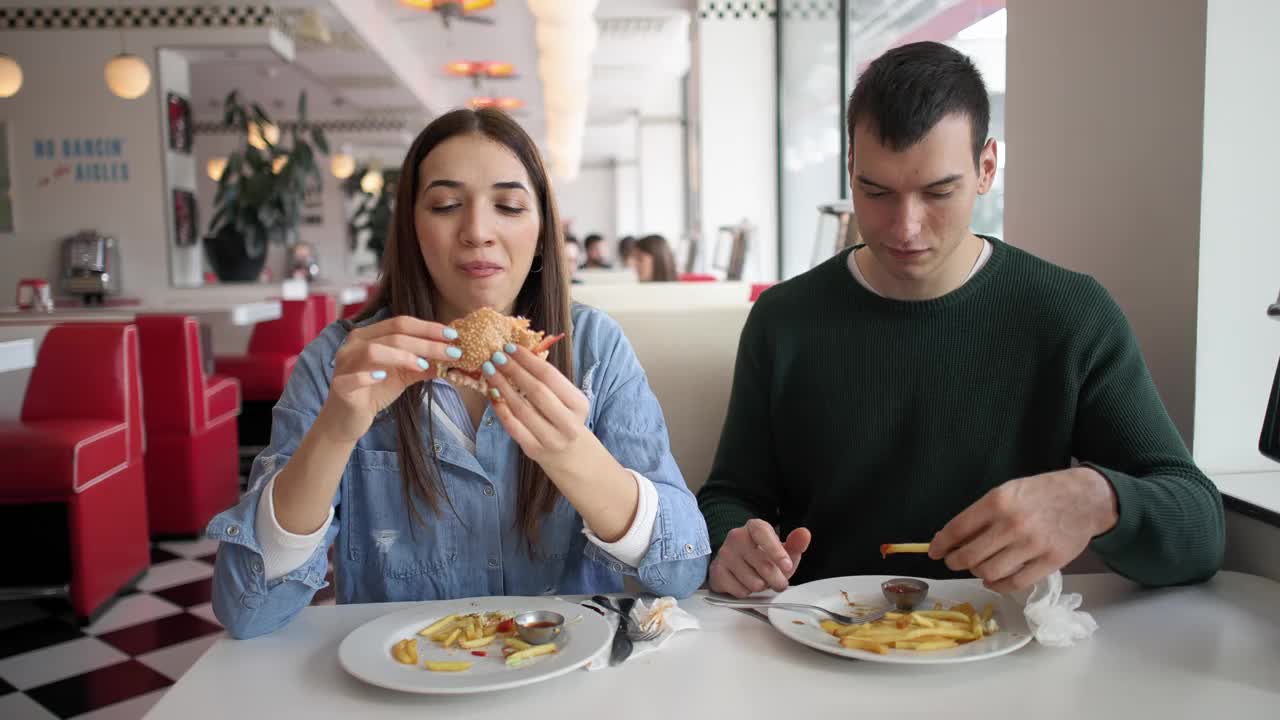 一对白人夫妇在一家复古快餐店里吃薯条和汉堡视频下载