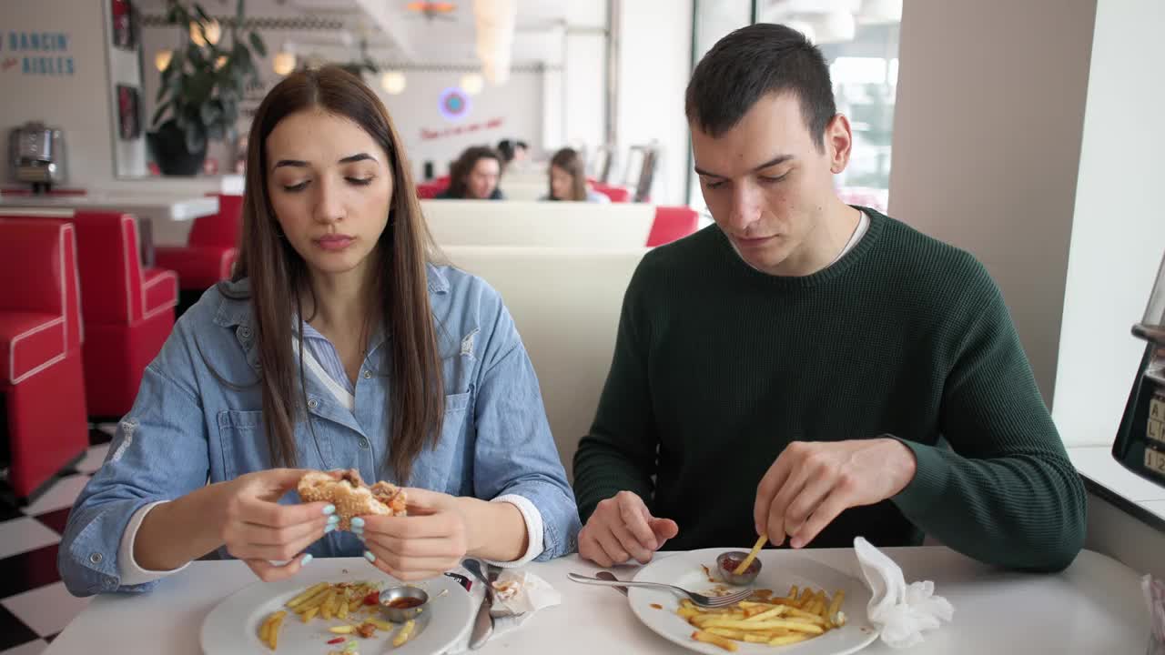 一对白人夫妇在复古快餐店里分享薯条视频下载