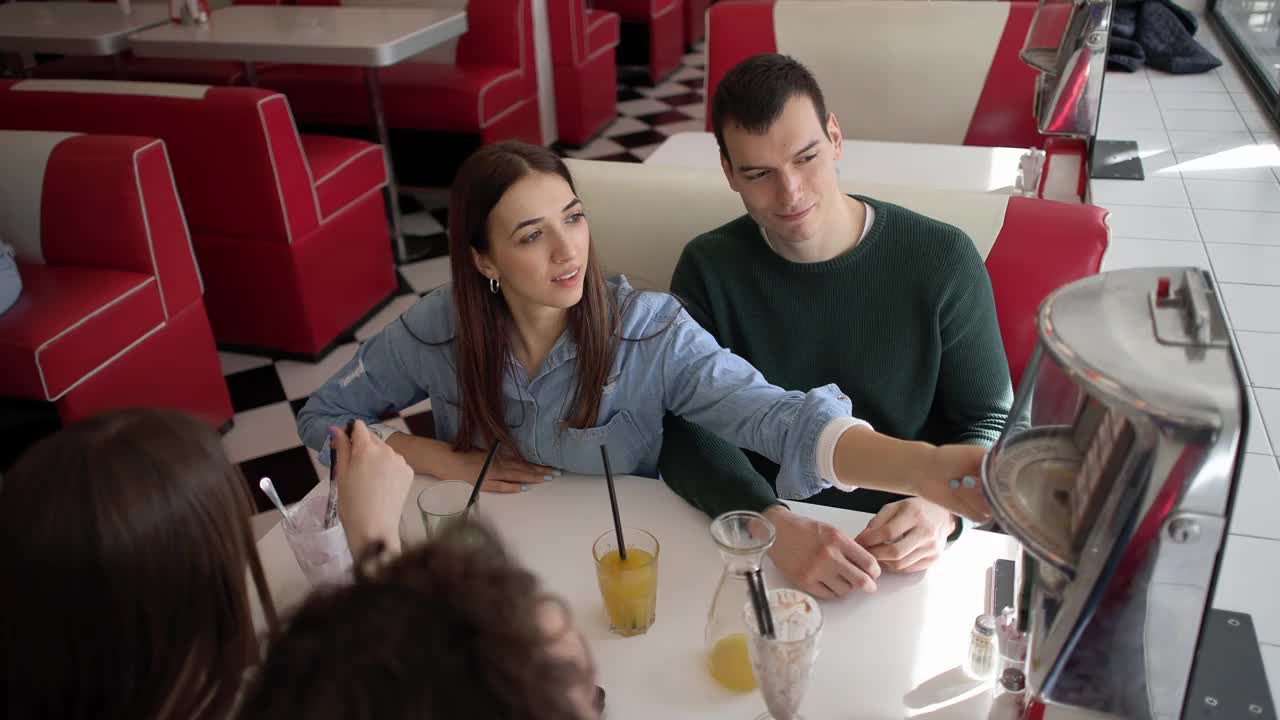 在一家复古快餐店的四人约会中，年轻的白人在自动点唱机上选歌视频下载