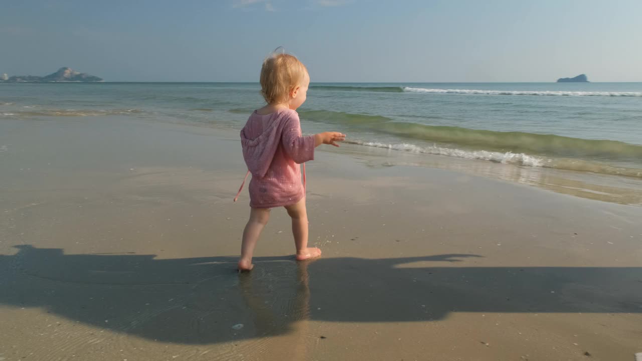 可爱的宝宝和妈妈在海滩上探索海水视频下载