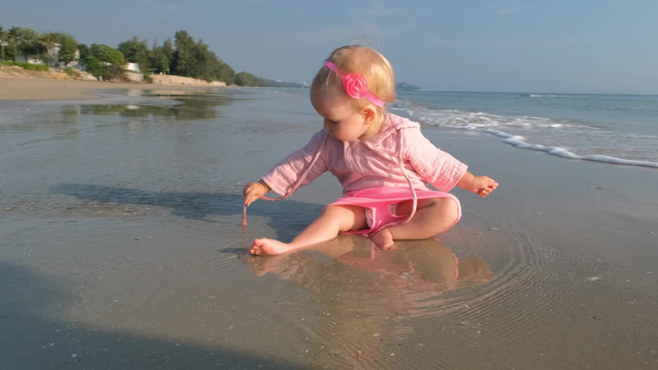 可爱的小女孩在玩沙子和海水视频下载