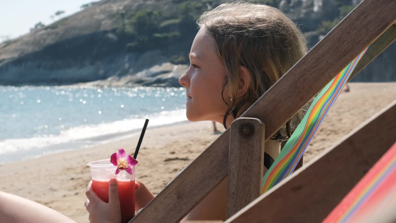 小女孩在海滩上喝水果鸡尾酒视频下载