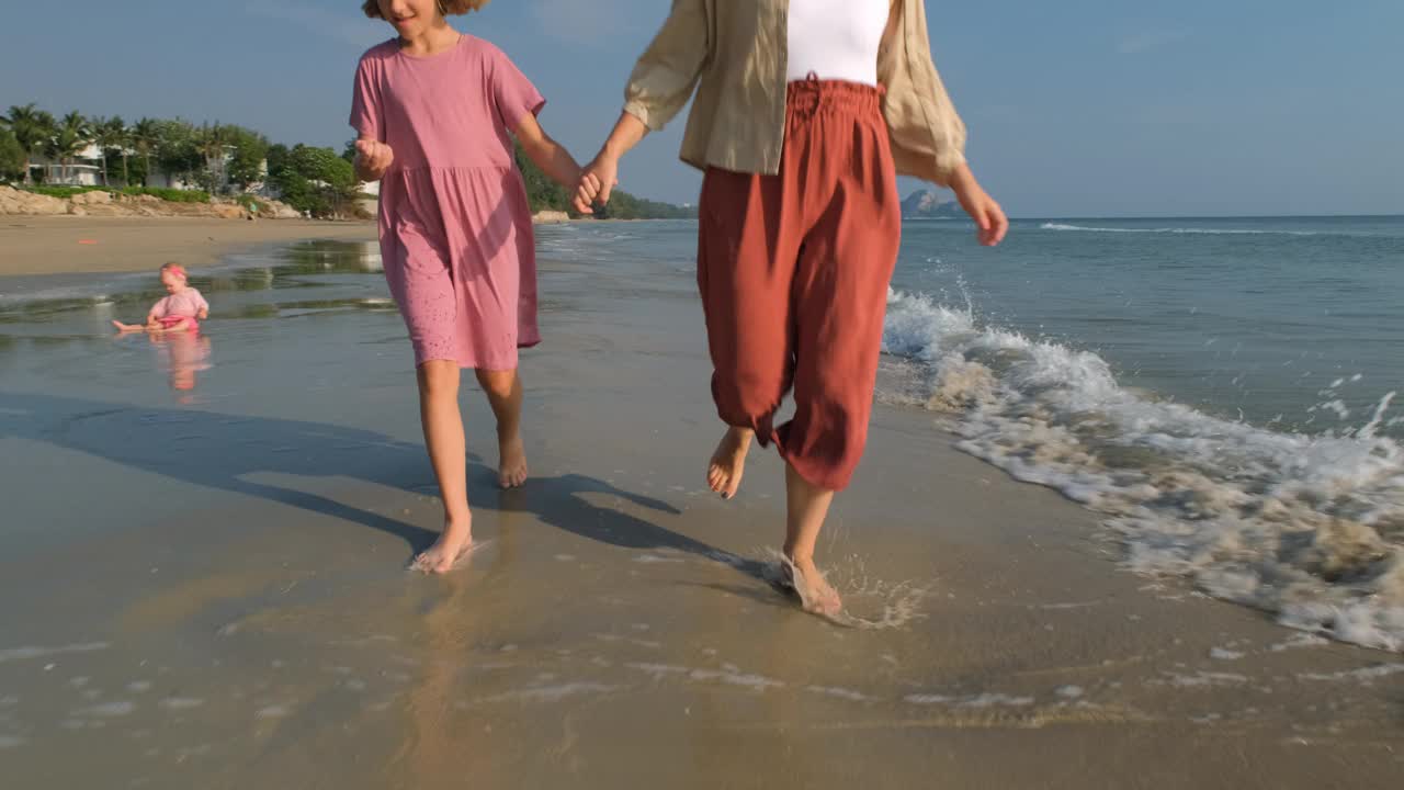 母亲和女儿沿着海滩海岸线奔跑视频下载
