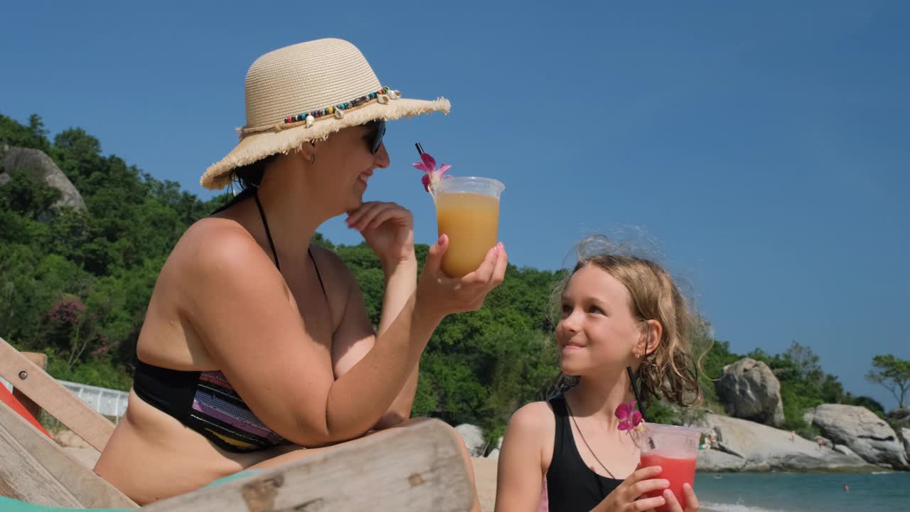 妇女和女儿在海滩上喝水果鸡尾酒视频下载