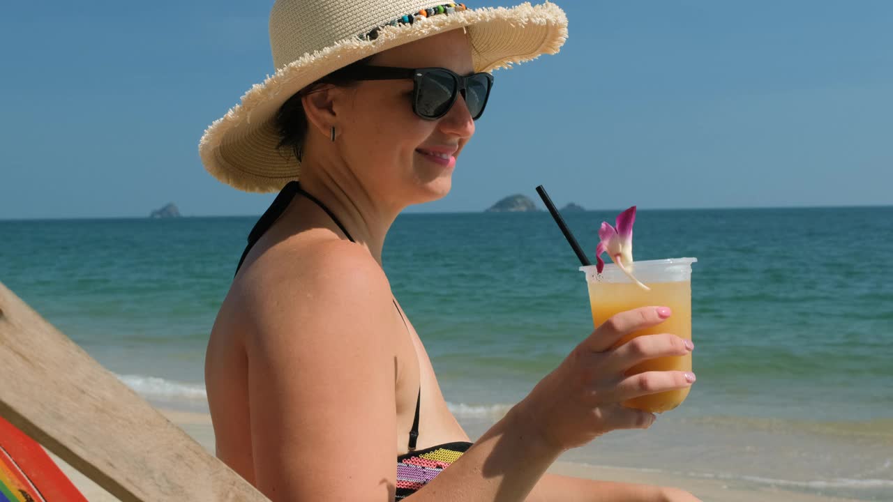 年轻女子在海边喝着水果鸡尾酒视频下载