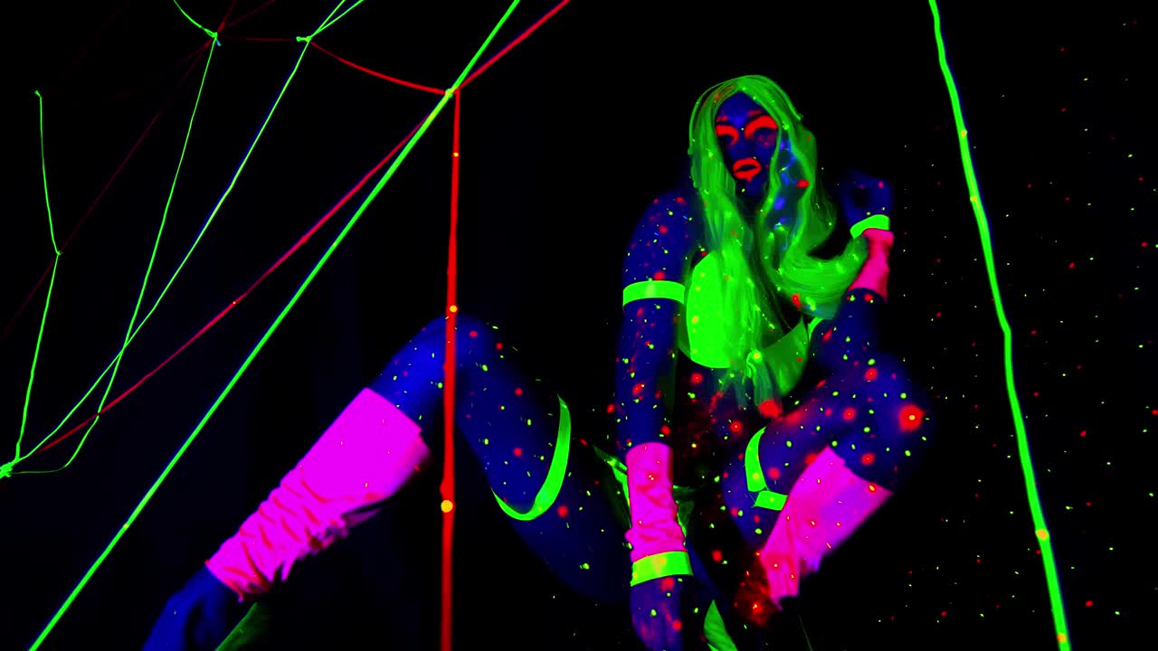 在紫外线下跳舞的女人身上发光的衣服和头发，梦幻效果，4k视频下载