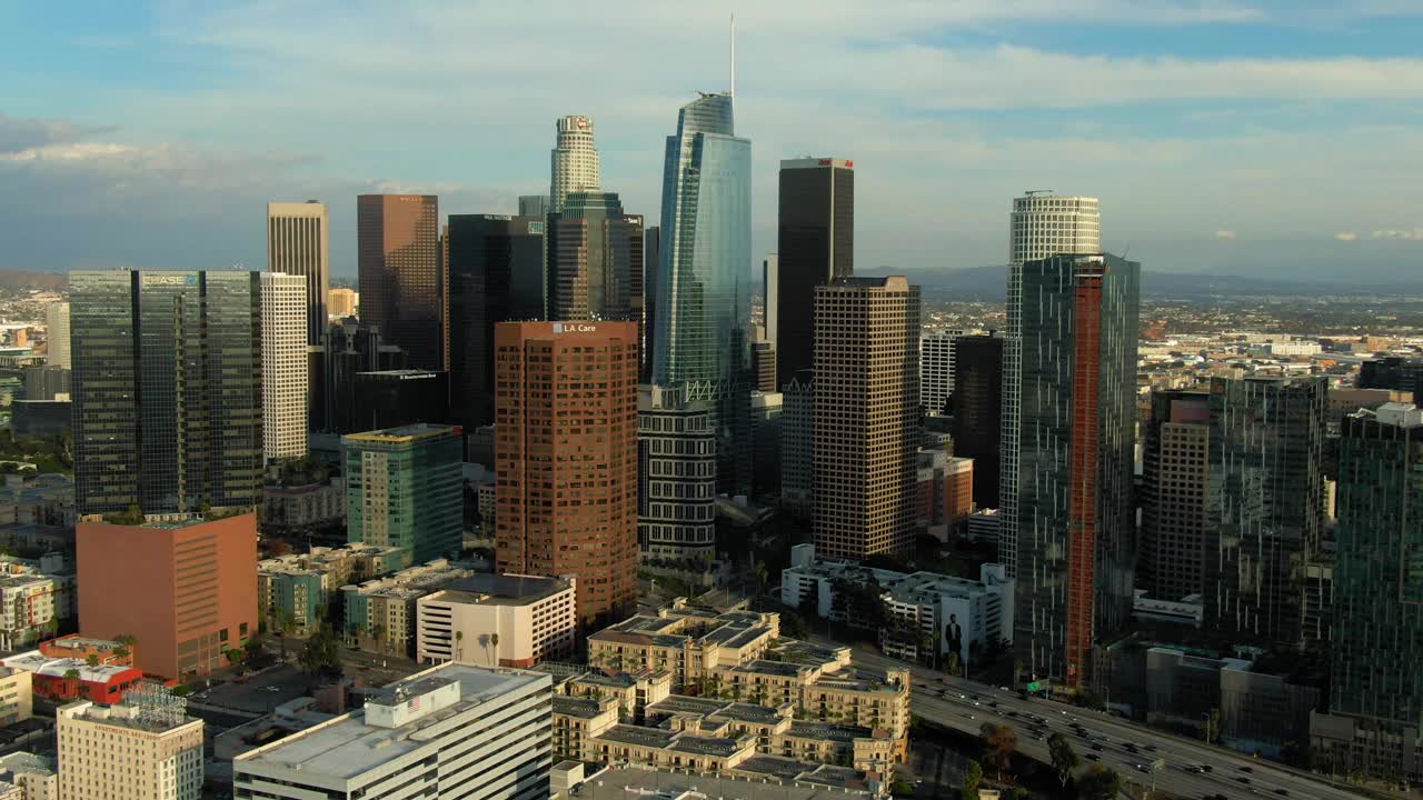 在多云的天空下，汽车在市中心的现代办公大楼中移动的航拍镜头-卡尔弗城，加利福尼亚视频下载