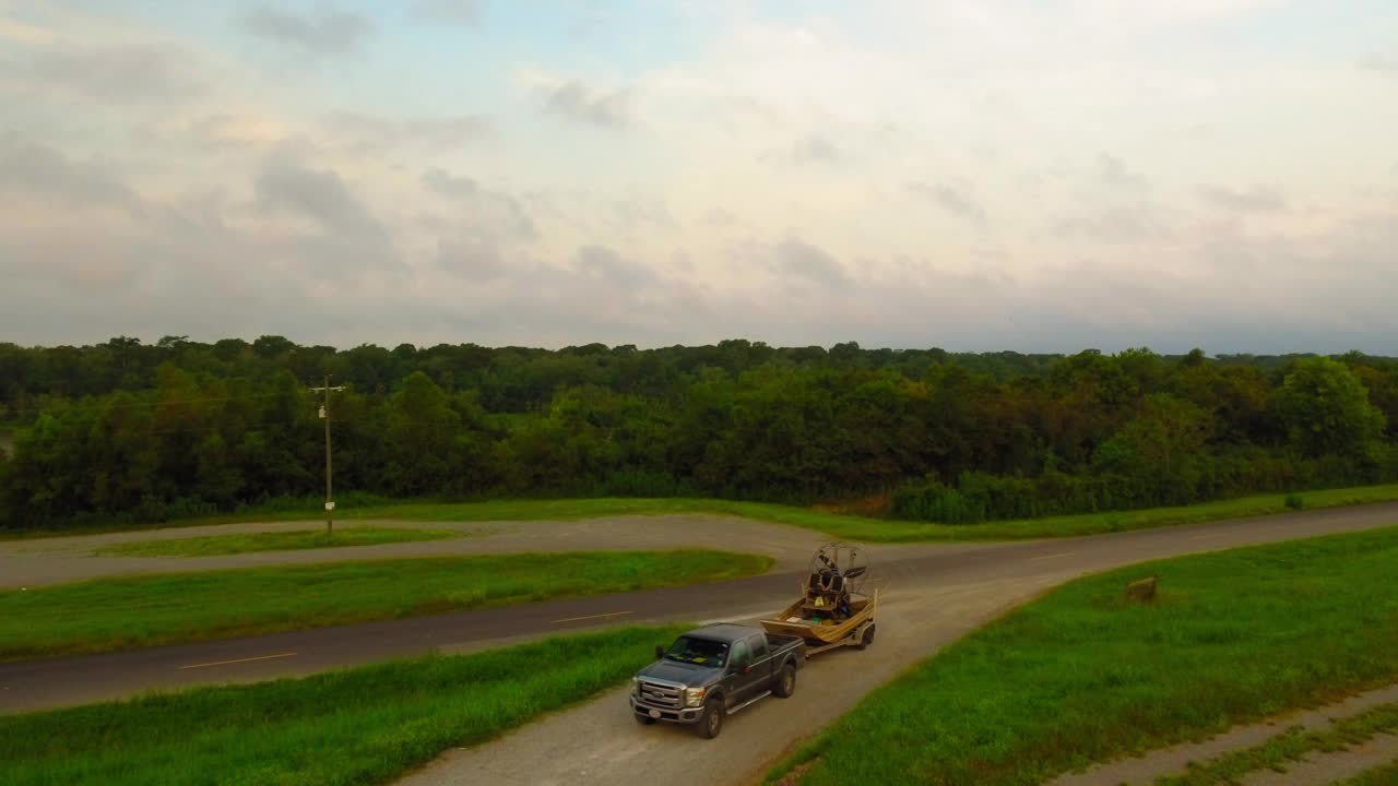 航拍:皮卡车拉汽船在路上，无人机在绿色景观上向后飞行- Bayou Vista，德克萨斯州视频下载