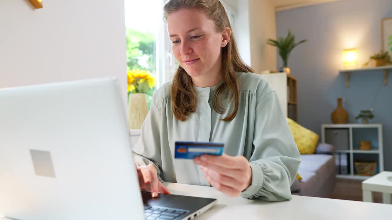 年轻的白人女性用信用卡在笔记本电脑上网购视频素材